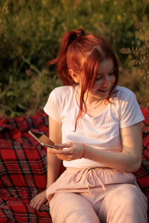 a red - haired woman looking down at her phone