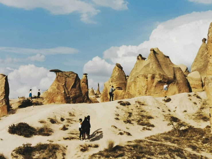 three people walking along a road through tall rock formations