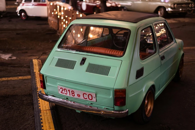 an older, mint green car is on the road