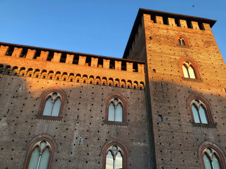 the sun is reflecting off the windows of the brick building