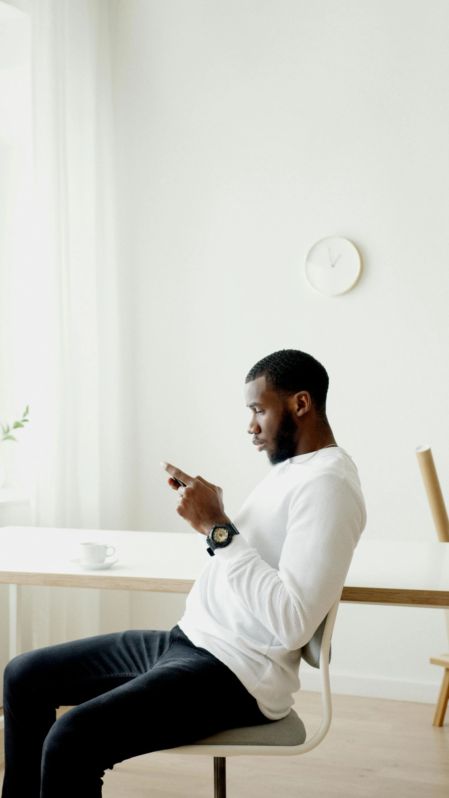 the man is sitting on his chair using the phone