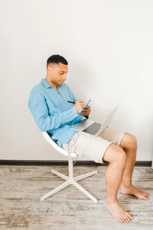 a man sitting on a white chair using his lap top