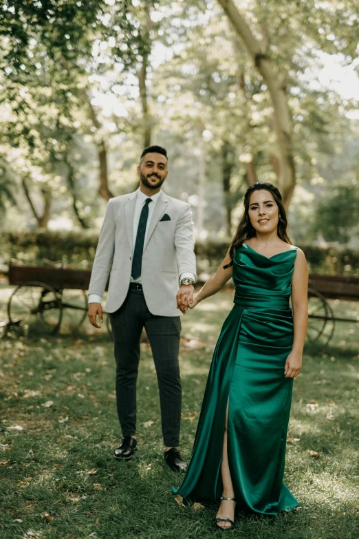 the couple are holding hands in the park