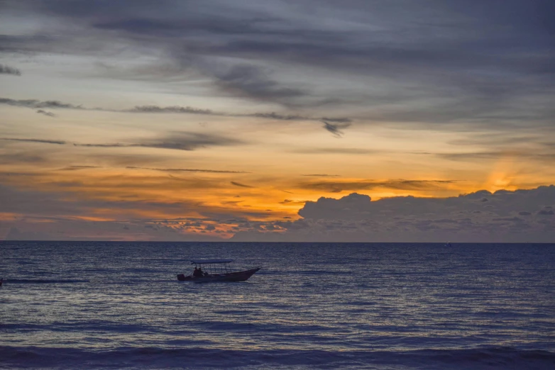 a boat is sitting out at sunset on the water