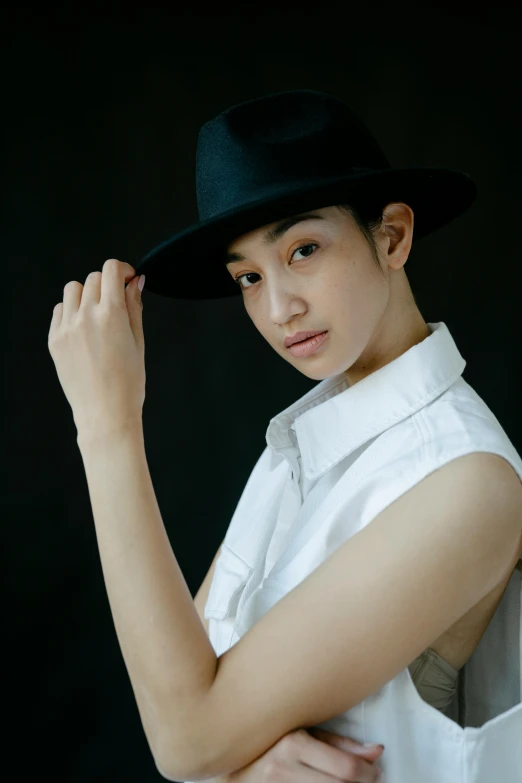 a young woman wearing a black hat and white dress shirt