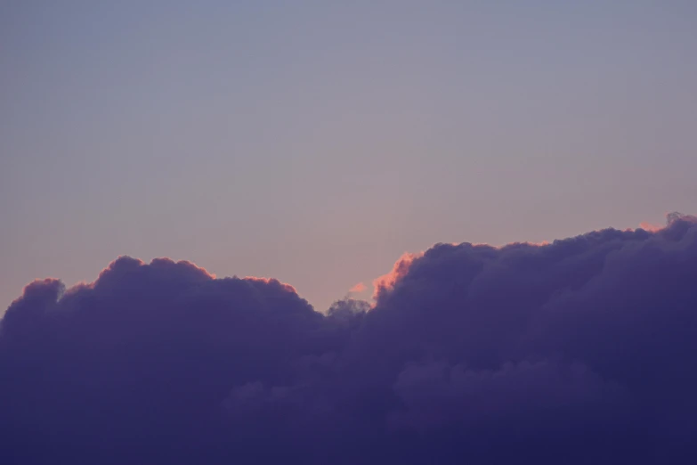 an airplane flying in the sky in front of clouds