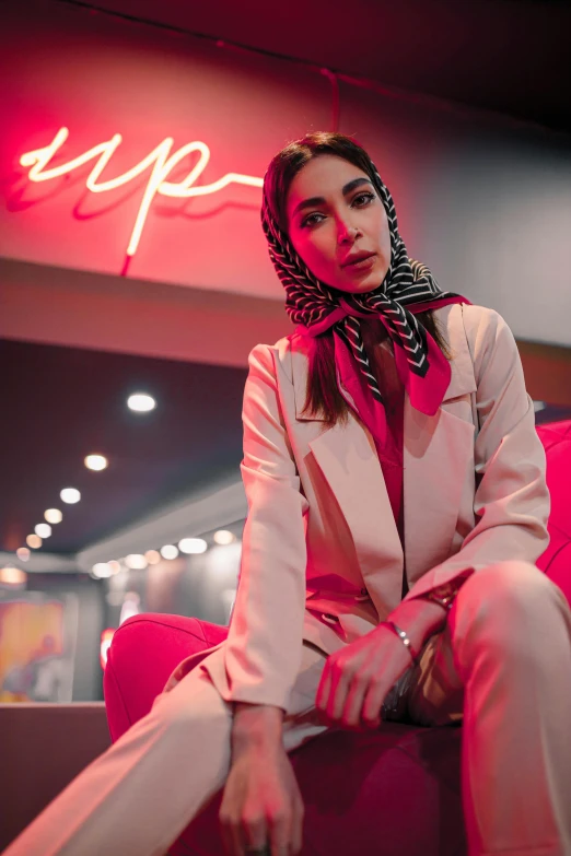 a woman in a tuxedo is posing in front of a neon sign