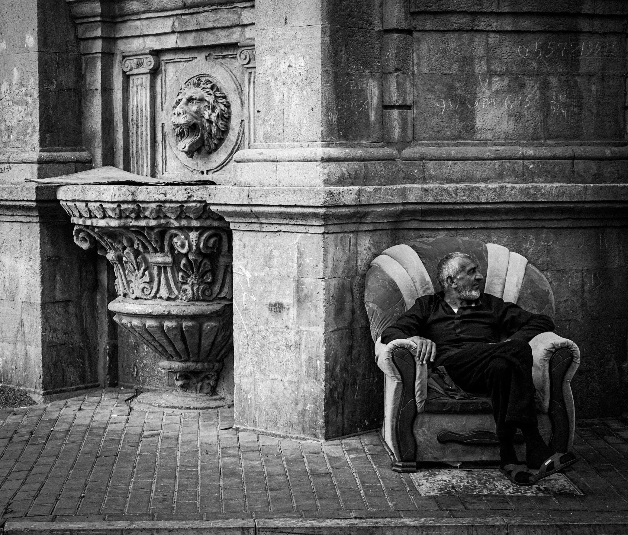 a man sits on a chair next to a building