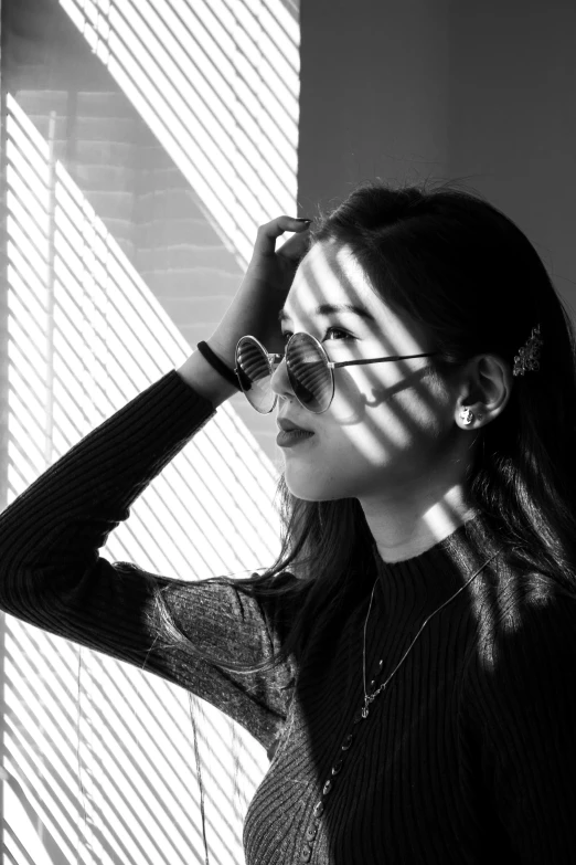 the young woman is wearing glasses next to blinds