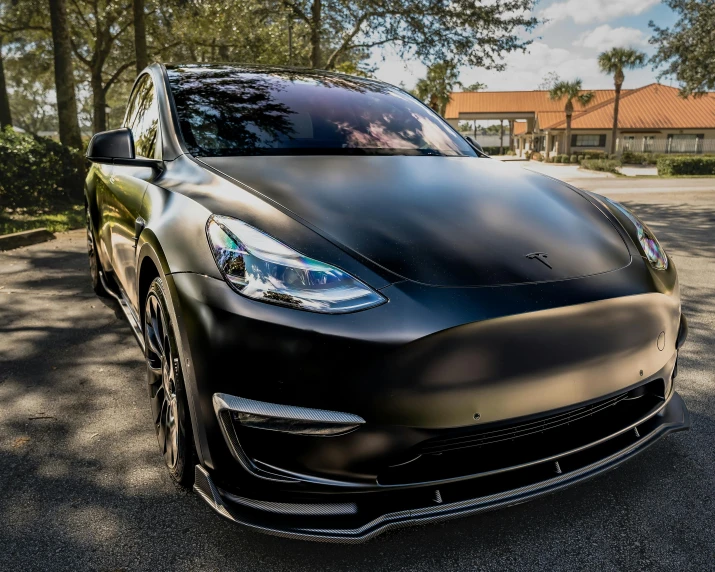 a black tesla is parked on the pavement