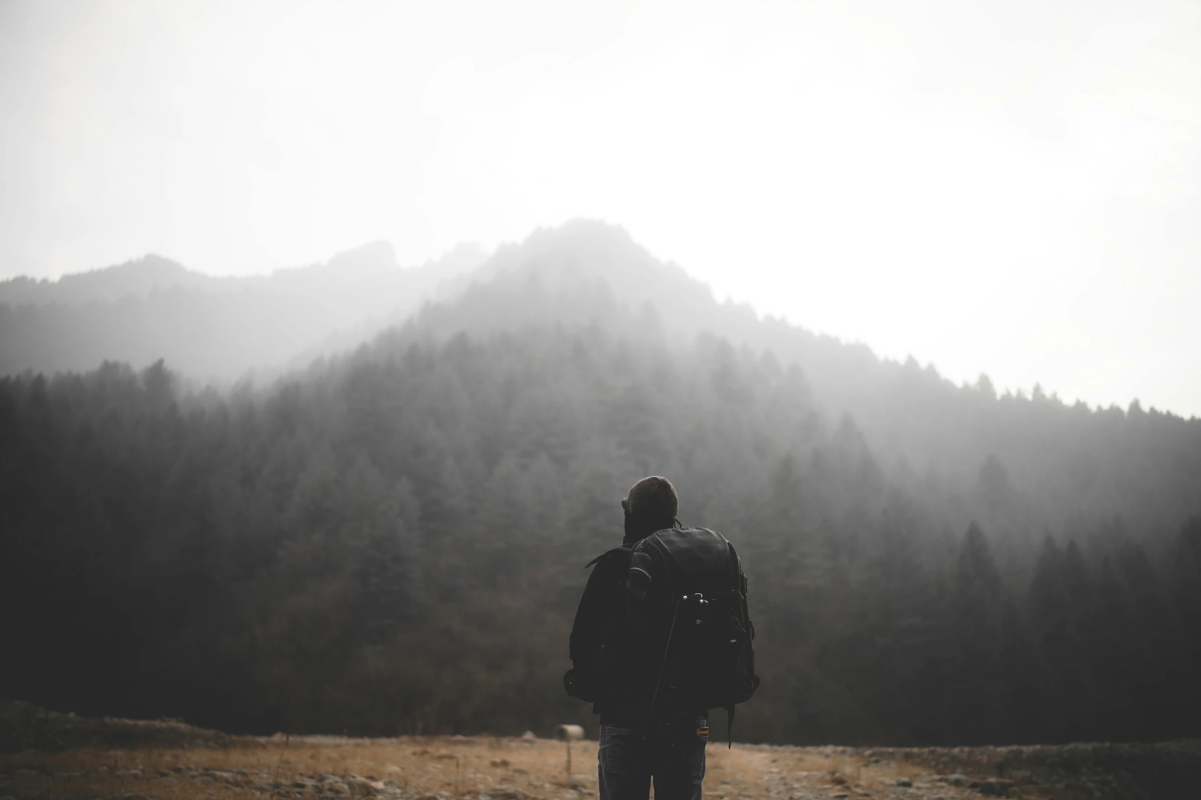 a man with a backpack and backpack standing on top of a hill