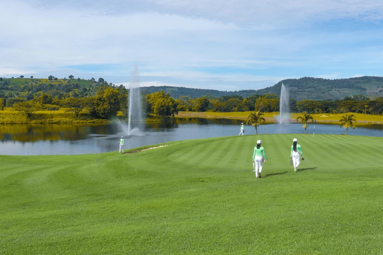 several people are on the golf course with fountains in the background