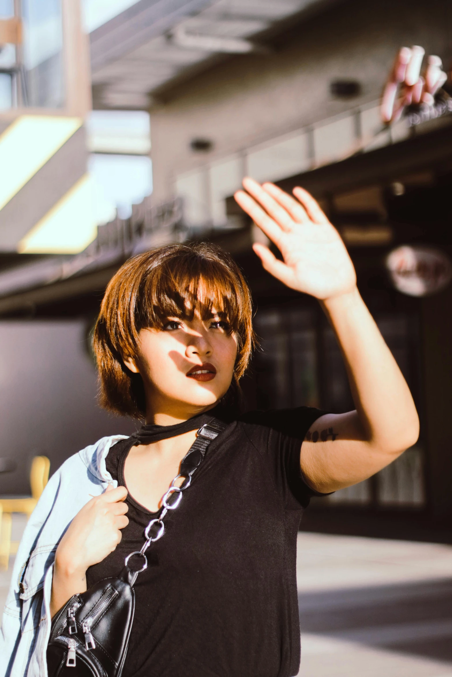 a woman waves goodbye standing on the side of a road