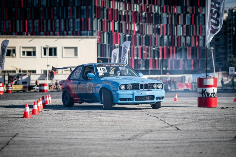 a blue car drives past orange traffic cones