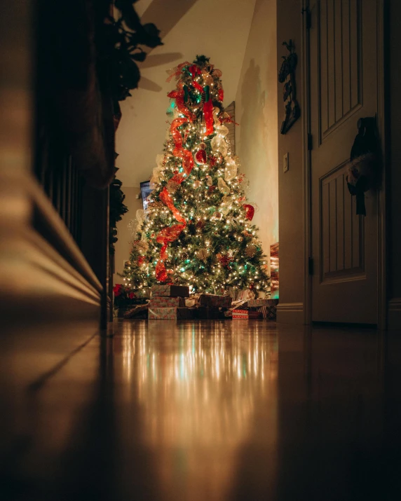 a lit christmas tree with red and green lights in the corner