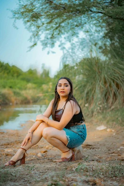 a beautiful woman in brown shirt sitting by water