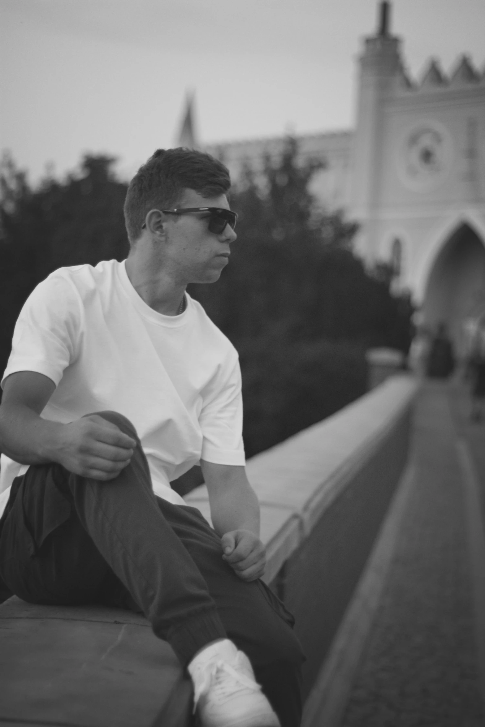 a man is sitting on a wall while he holds his hat