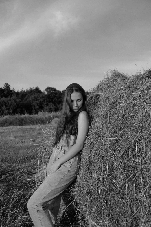 a woman posing by the bales in a field