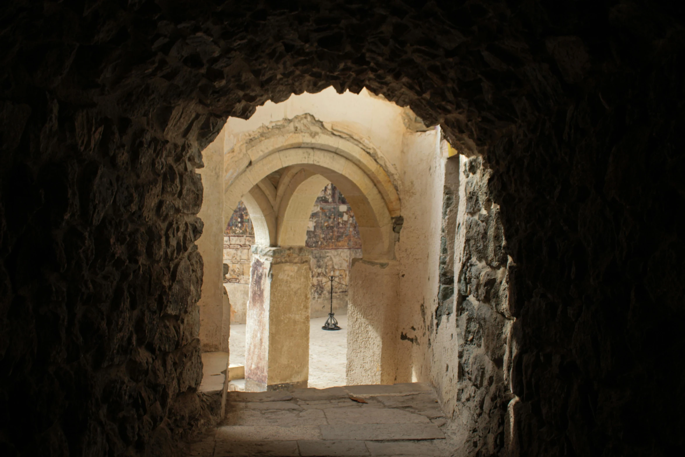 a stone archway in an old building with chandeliers