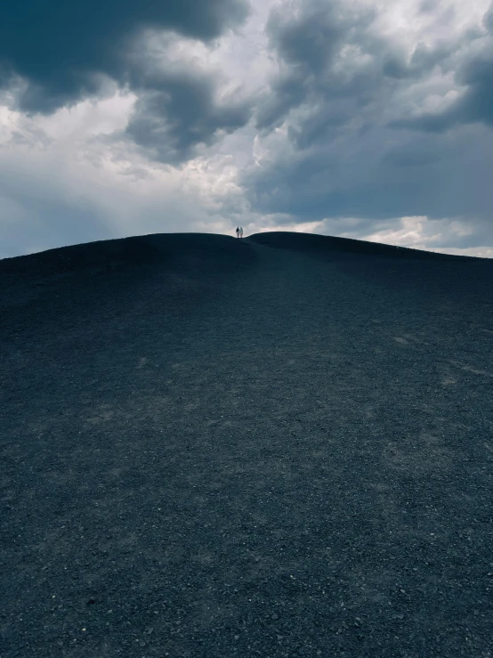 the lone person standing on a hill under clouds