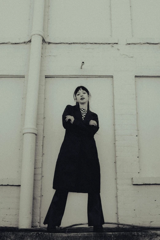 black and white po of a woman leaning against a building