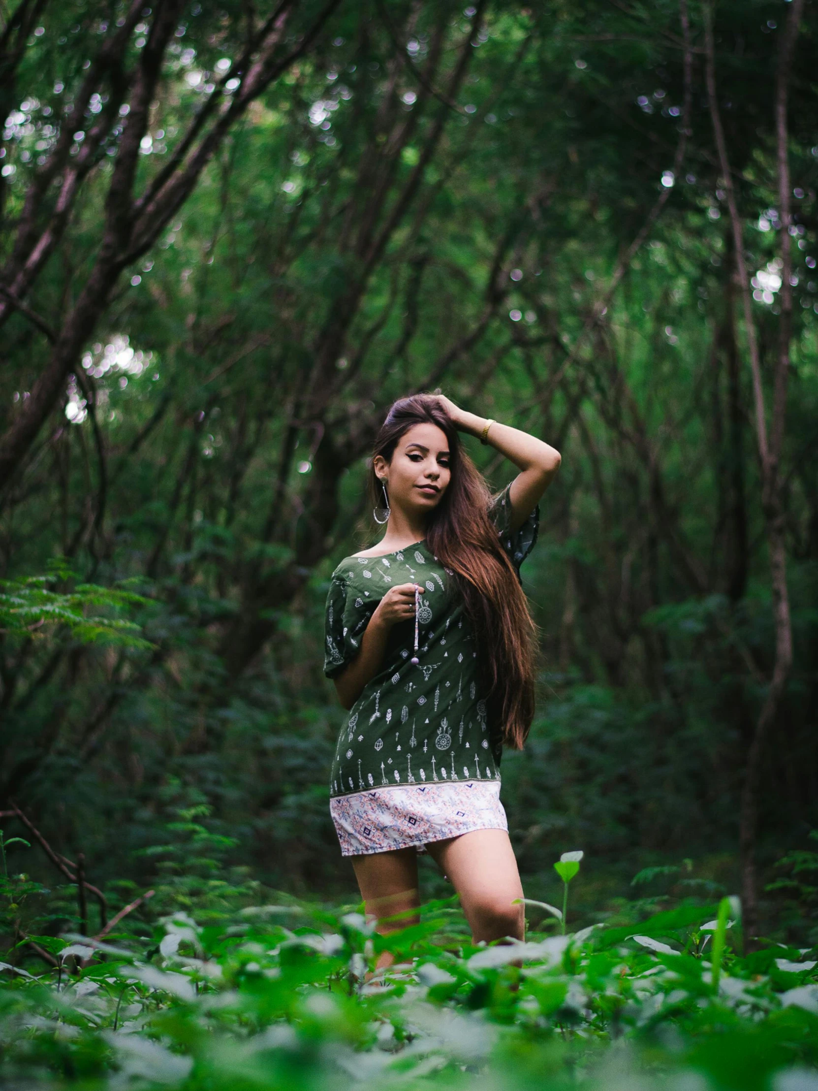 young woman in a wooded area with trees behind her