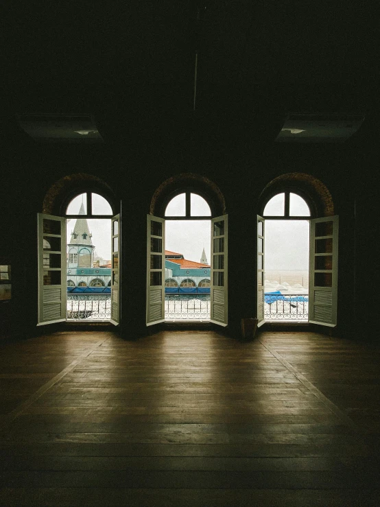 an open room with three open windows and a deck