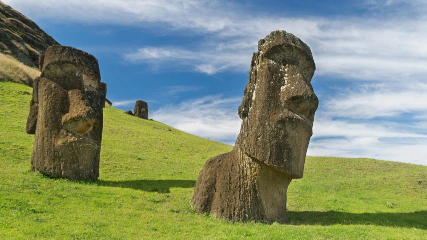 three statues stand on the hill top against a blue sky