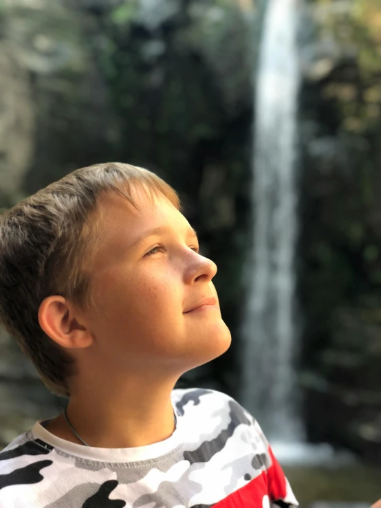 a  is standing in front of the waterfall