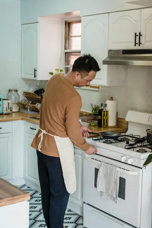 a man wearing an apron and cleaning his stove