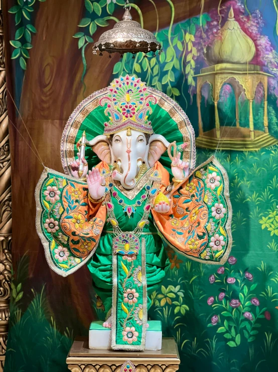 colorful sculpture of ganesh, surrounded by green and orange background