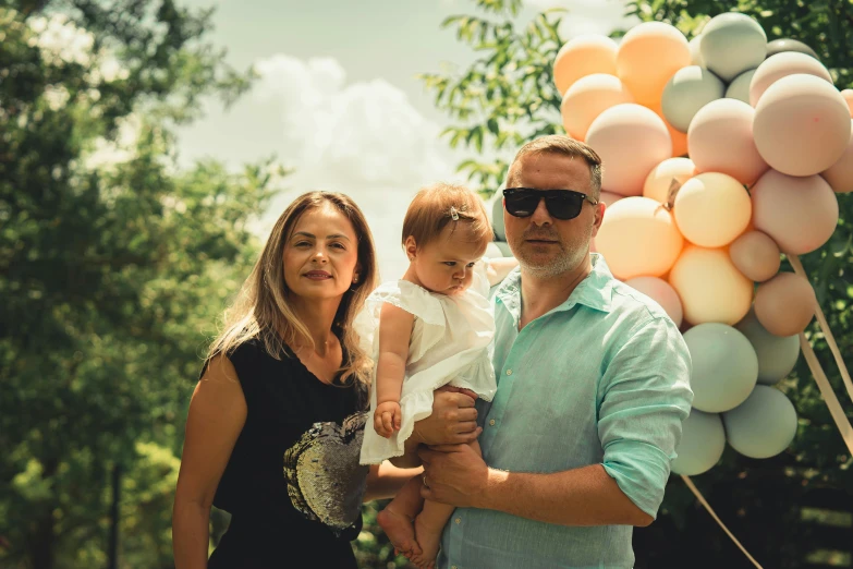 a man is holding a little girl next to balloons