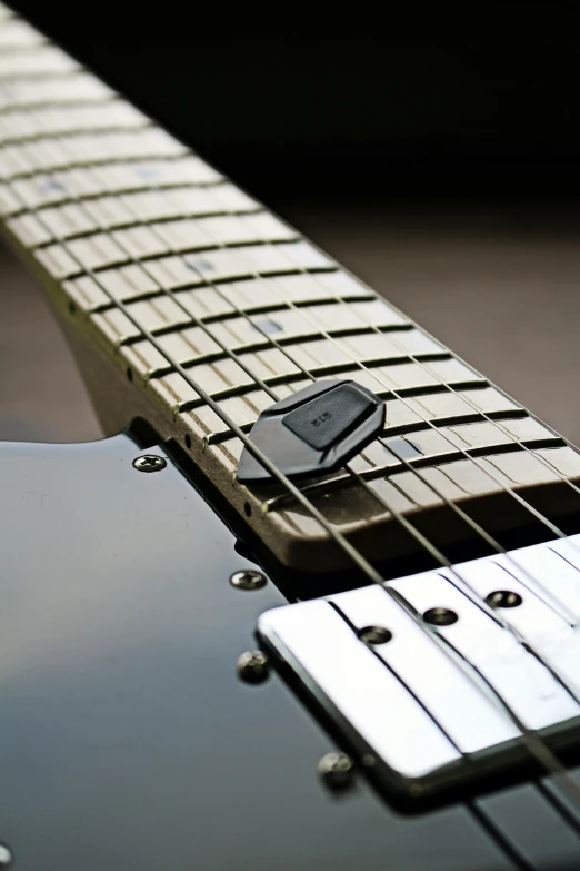 a close up of a black guitar with the pick up on highlighted