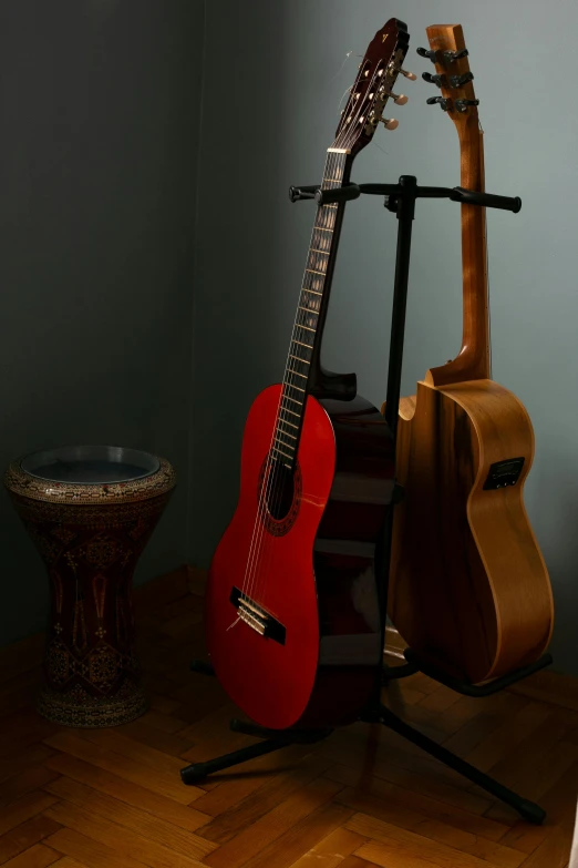 a red guitar leaning up against a wall in front of a small stool