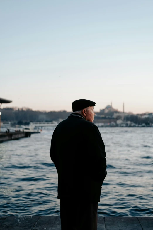 a man wearing a black coat by the water