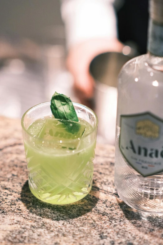 a beverage with a lime sits next to a bottle