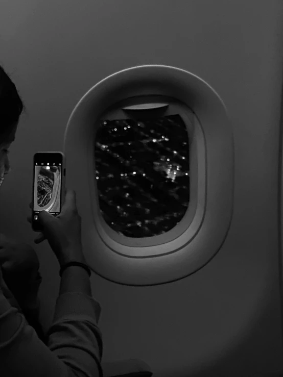 a person holding a cell phone taking a po of the city from an airplane window