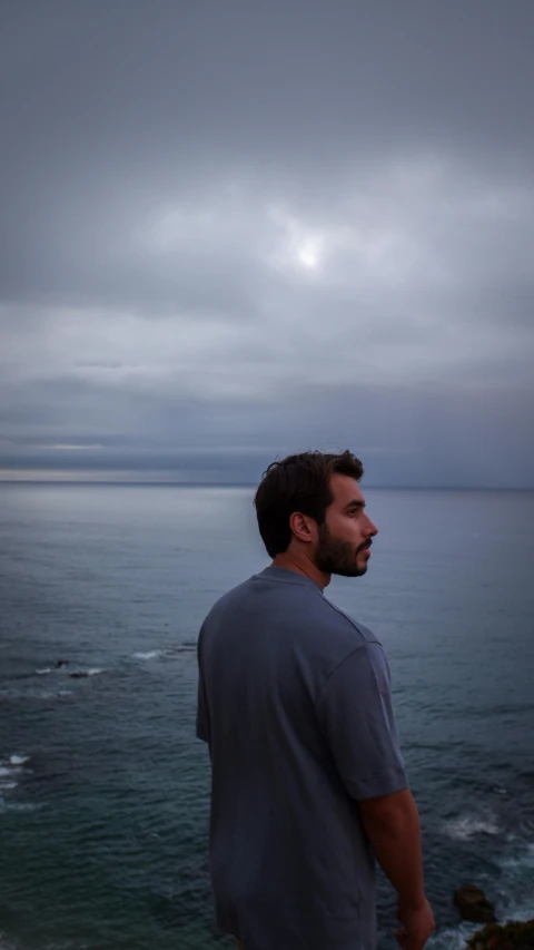 a man that is standing on a hill near the ocean