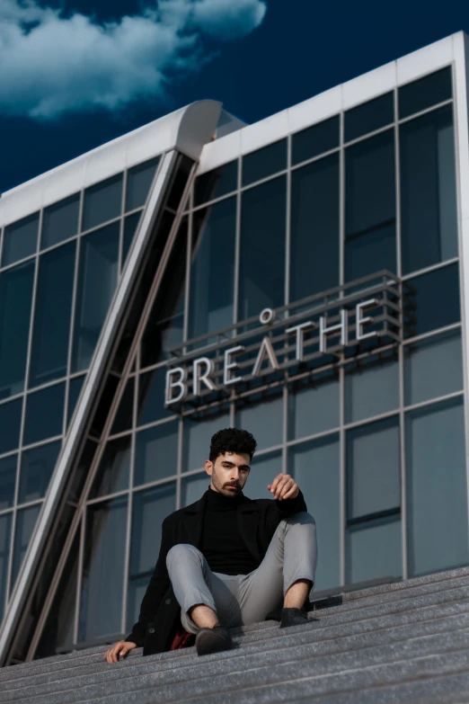 a man in a black shirt is sitting on a set of stairs