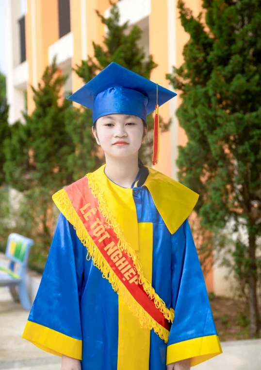 a  poses for the camera in his blue and yellow graduation gown