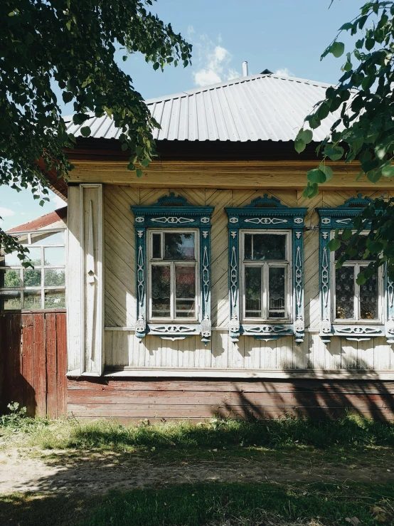 a small white building with blue windows and a red wood bench