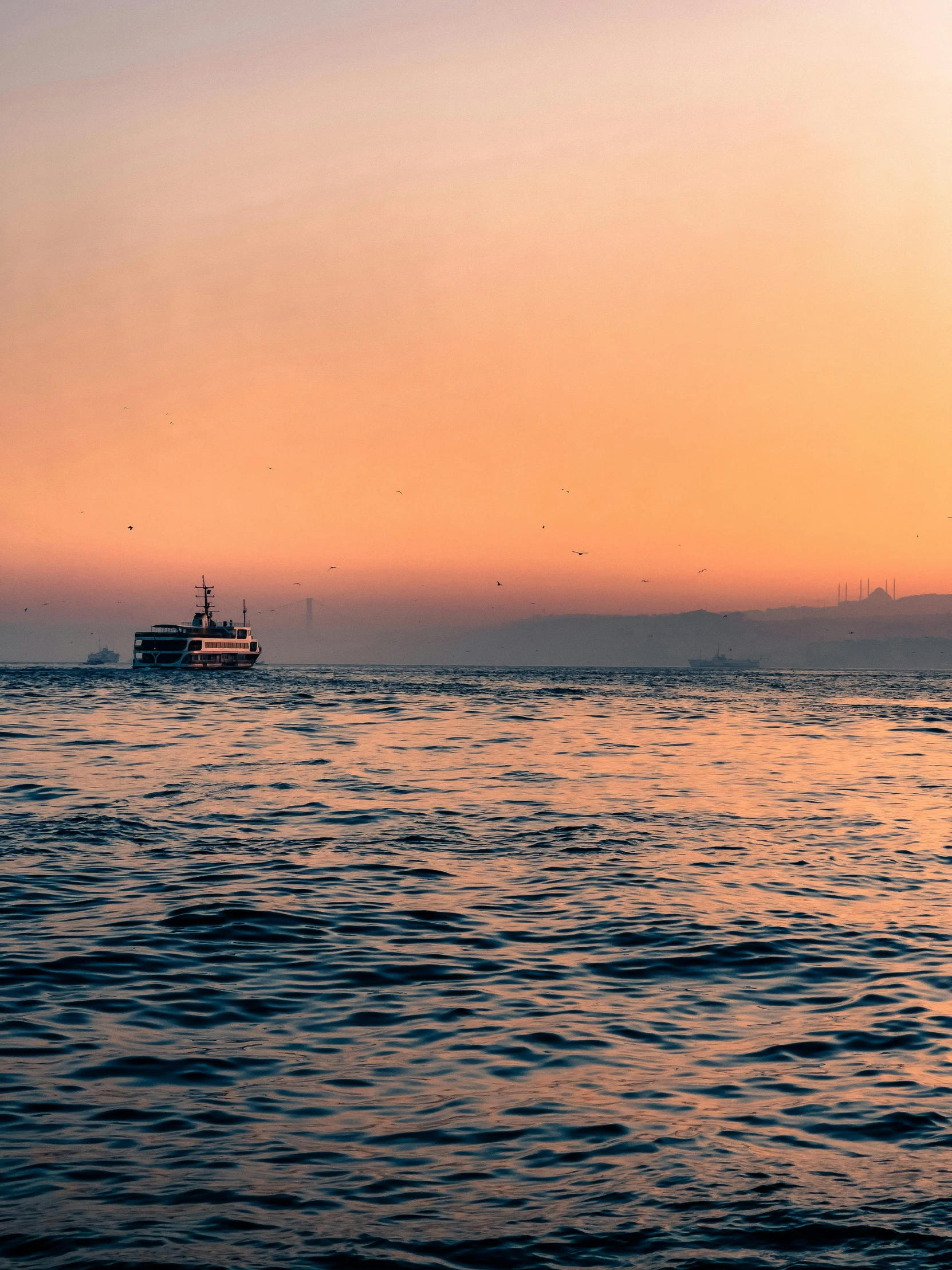 large boat at sea at sunset with small ship in distance