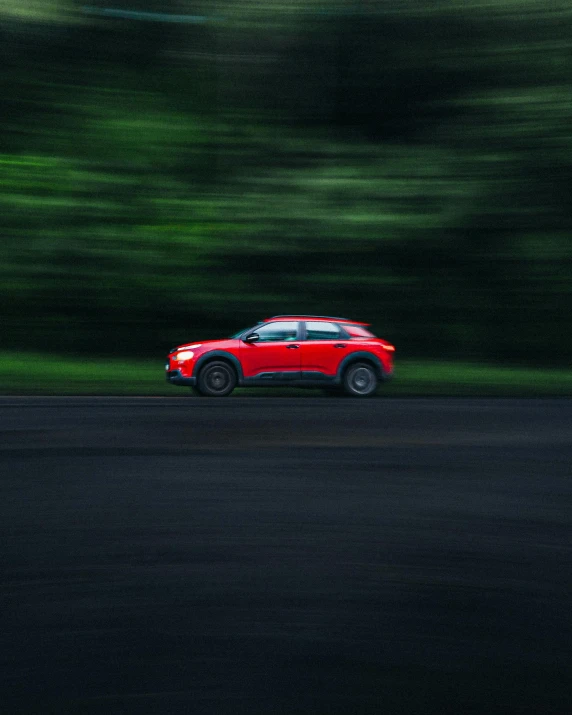 a red car is moving fast on the road