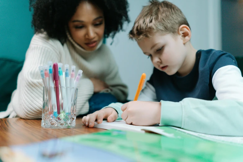 a girl and boy using pens to color