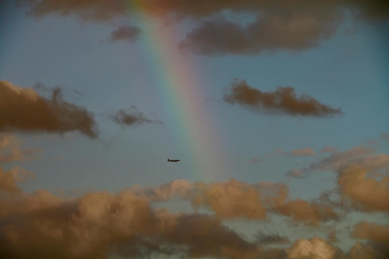 the plane is flying by under a rainbow