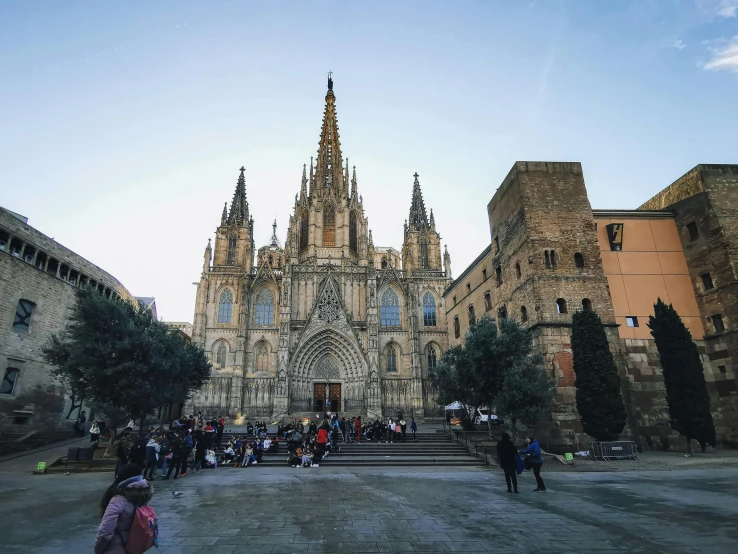 several people walk in front of a large cathedral