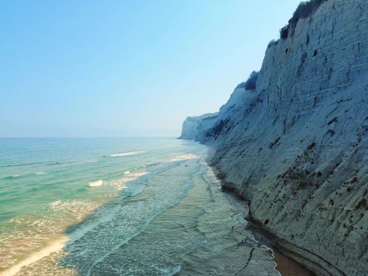 a cliff side on a beach with clear blue water