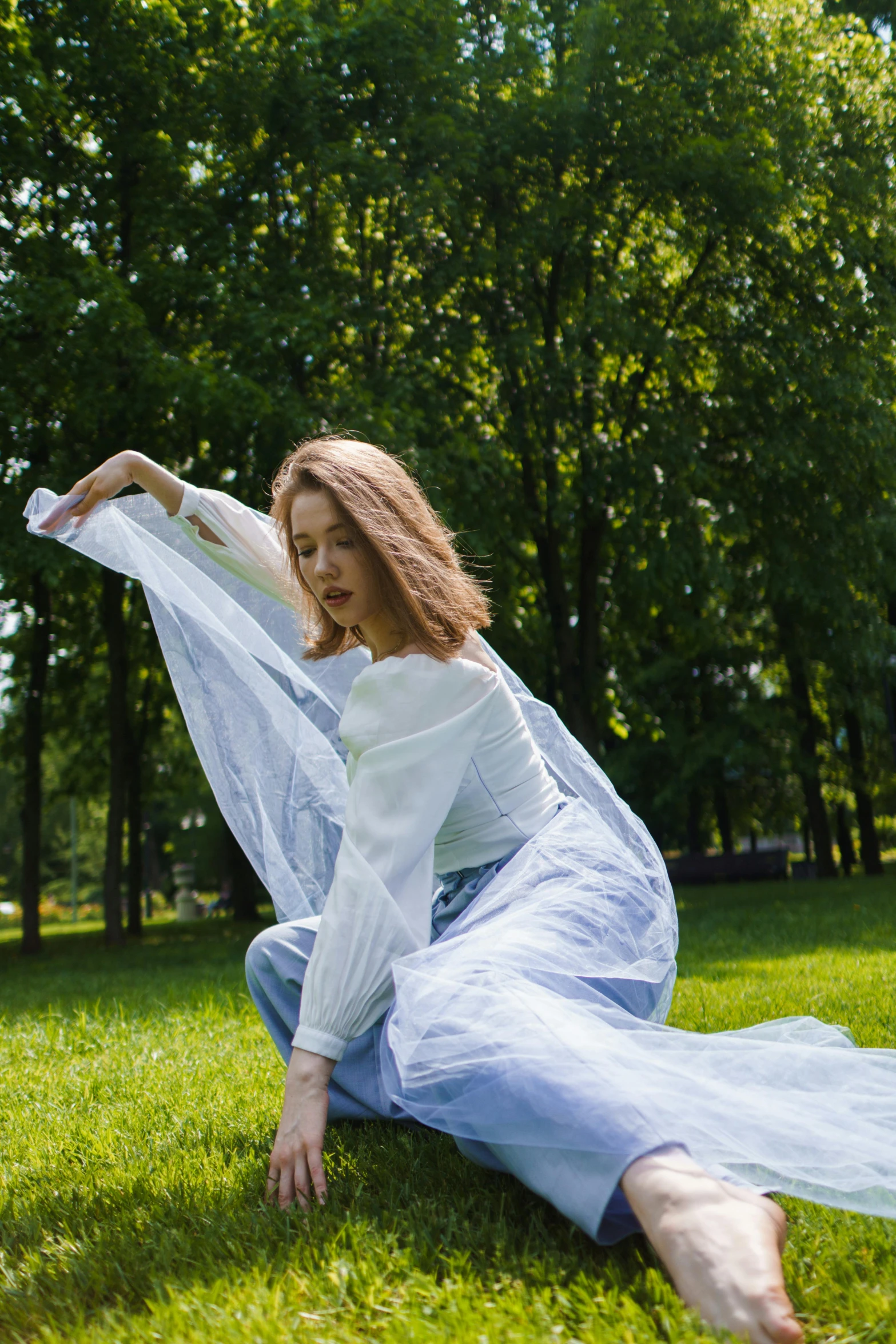 woman in long white dress sitting on grass posing for picture