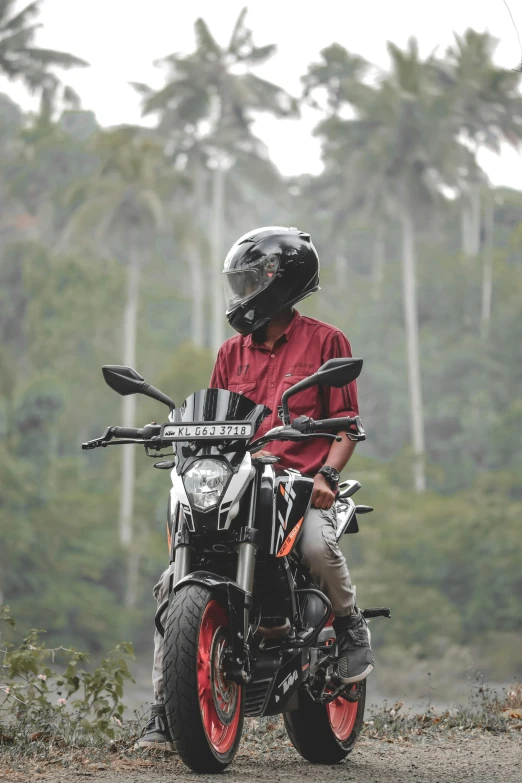 a man in red shirt sitting on motorcycle with helmet on