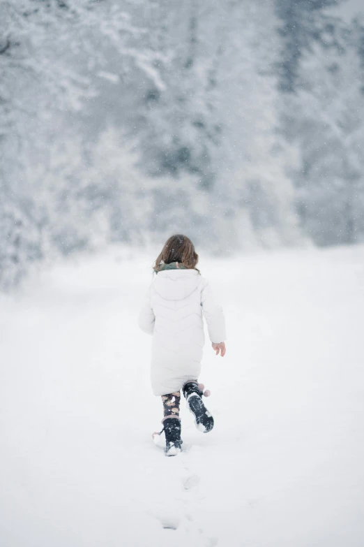 a child walking in the snow with a jacket on